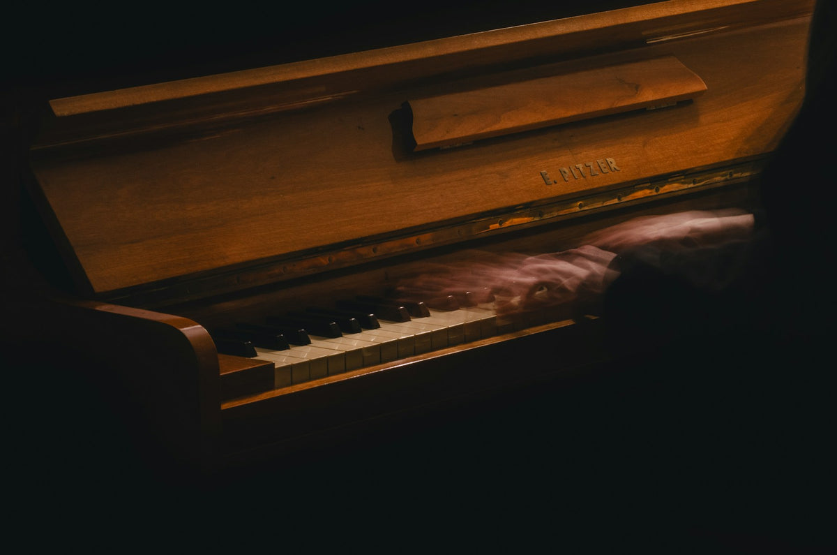 Hands playing piano in dramatic low light